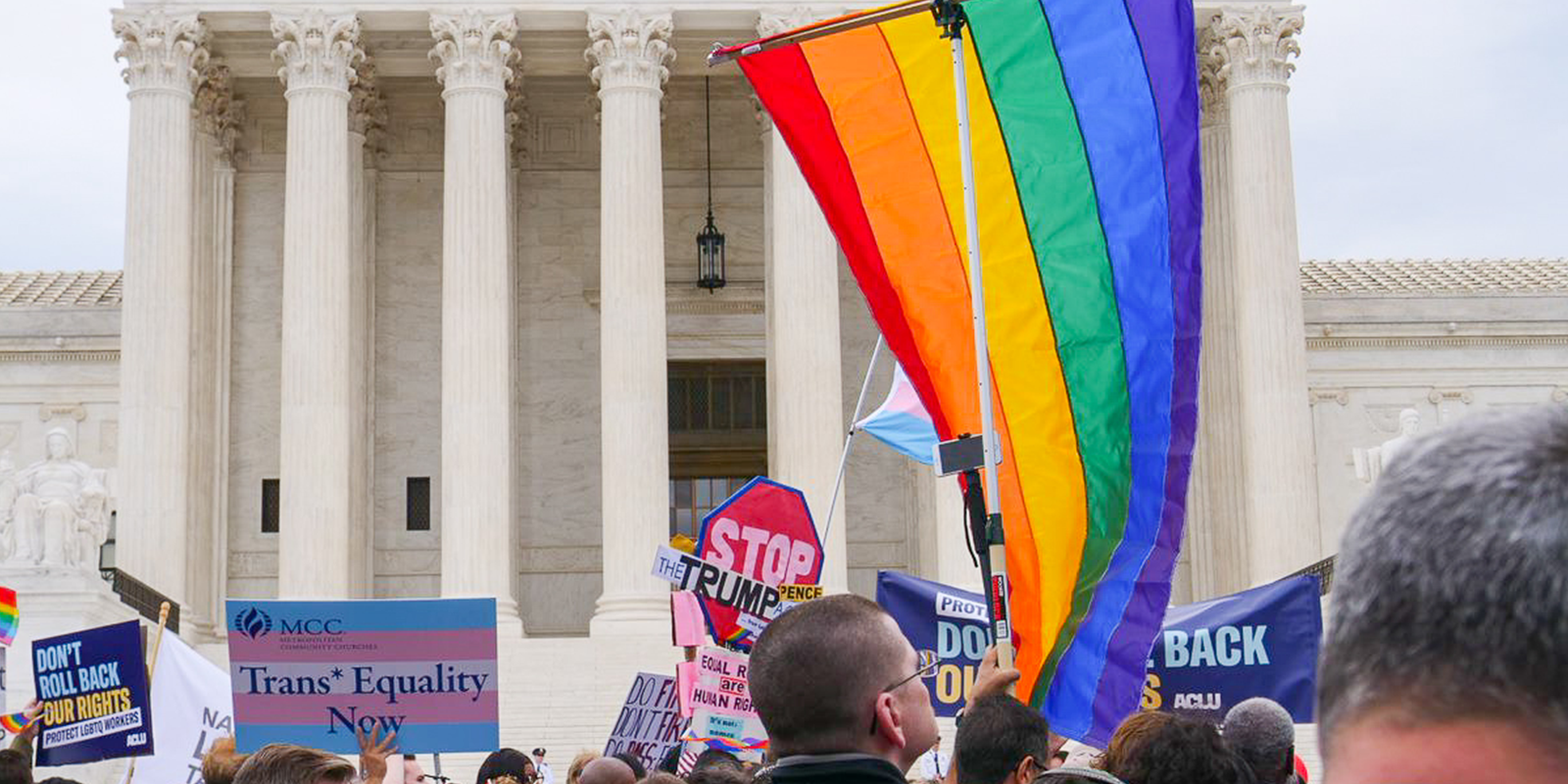 Gay pride flag in front of supreme court entrance with pro-LGBTQ equality signs